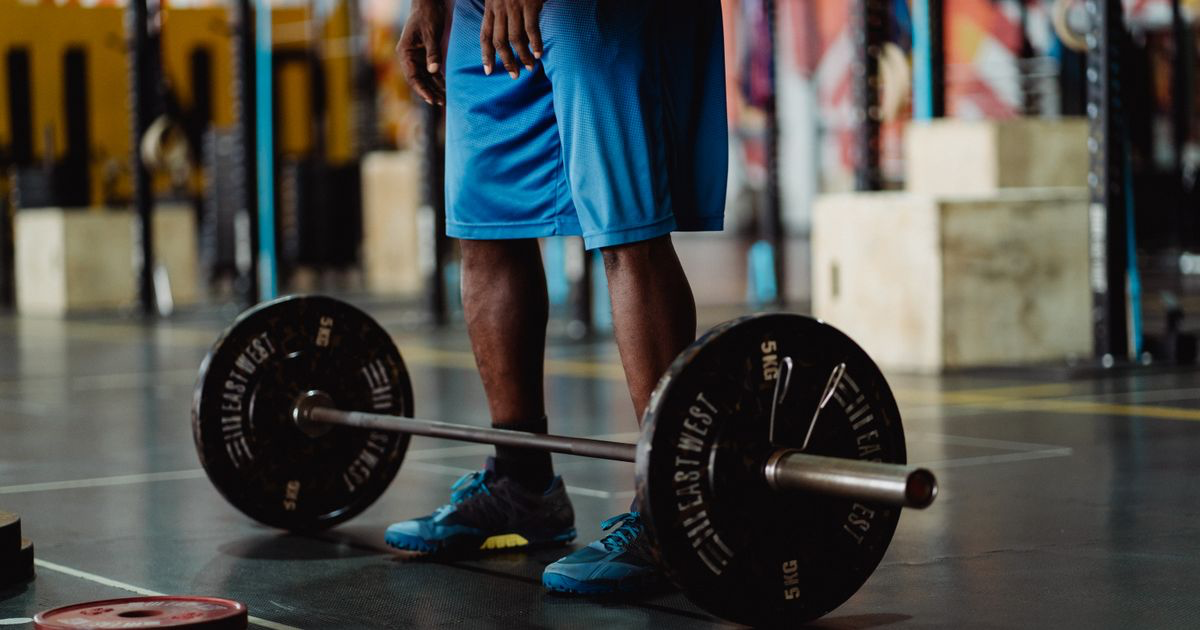 A loaded barbell on the gym floor beside a lifter, the kind of session an Alpha Progression alternative has to track