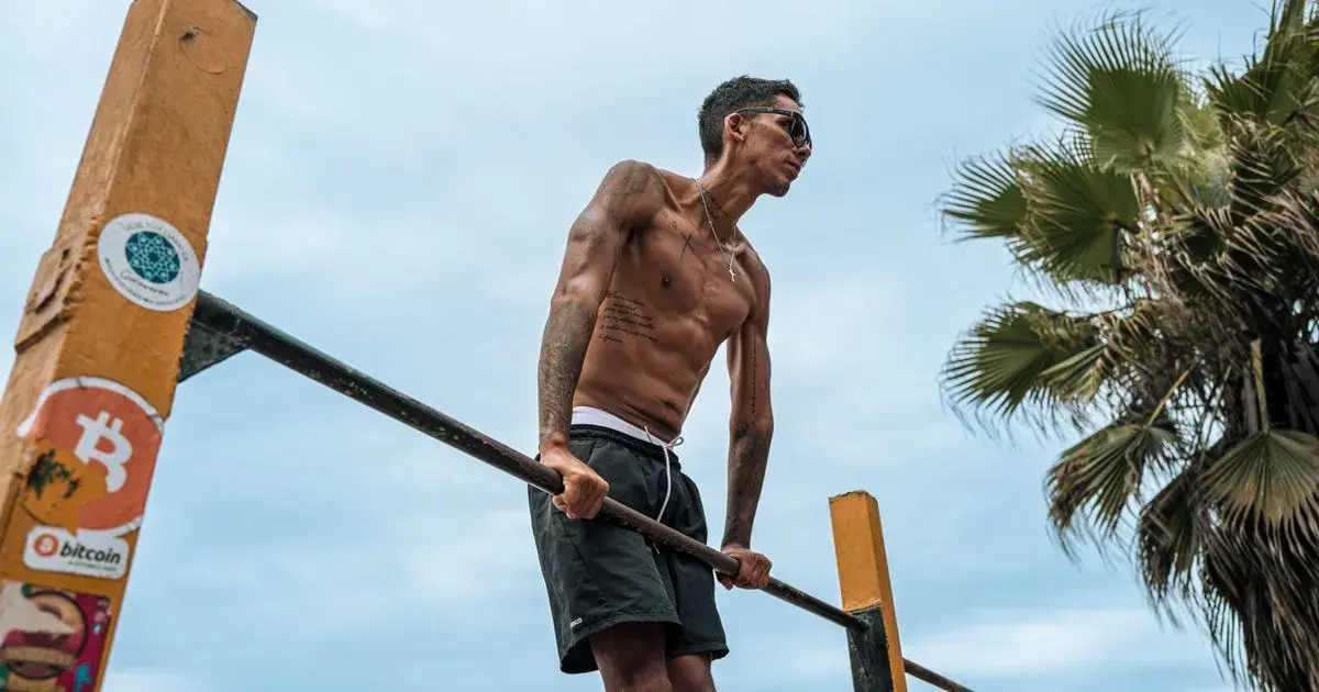 Man doing a parallel bar dip outdoors as part of a calisthenics workout plan