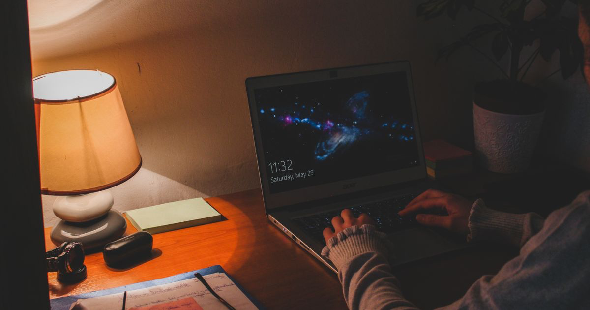 A person working late on a laptop by lamplight, building an indie iPhone workout app
