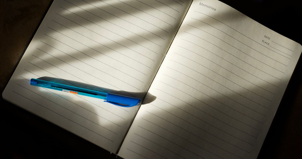 An open gym workout notebook with a pen and a date field, ready for logging lifts