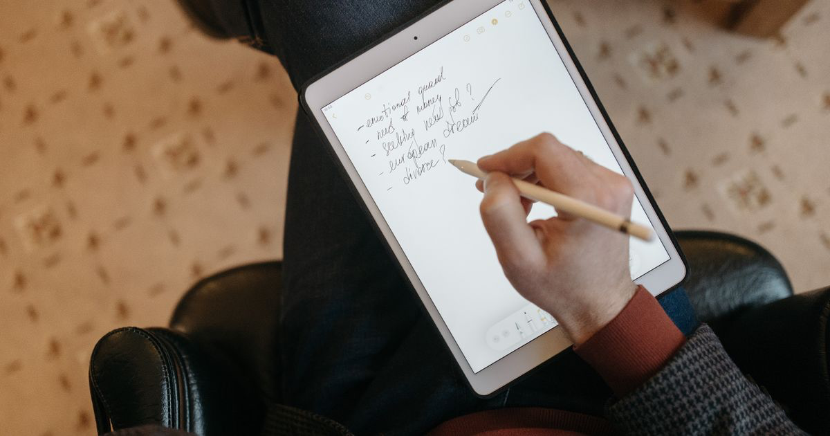 Person handwriting a Notability workout template on an iPad with a stylus