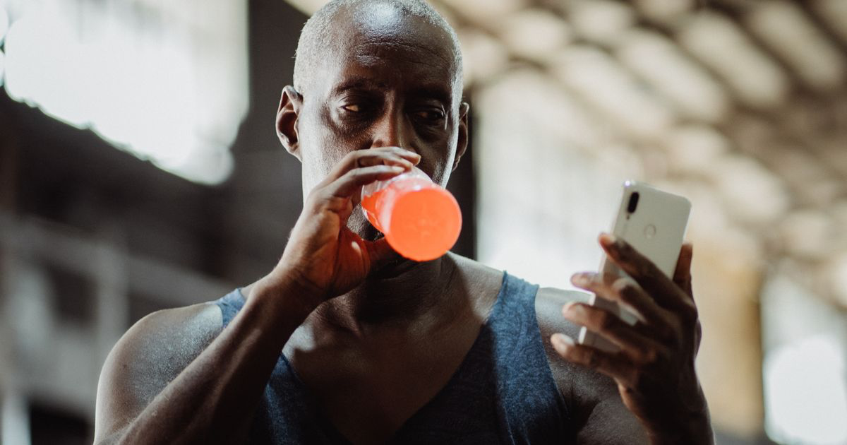 Lifter checking his phone in the gym, the moment a OneNote workout tracker template gets filled in between sets