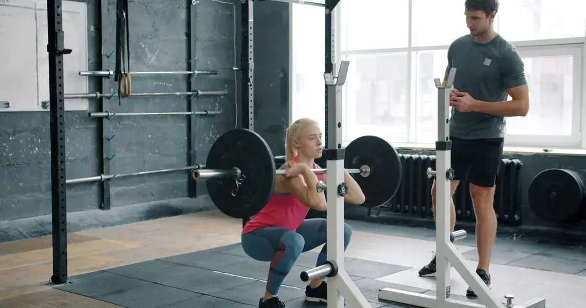 A lifter performing a barbell front squat in a gym, the core lift in the StrongLifts 5x5 program