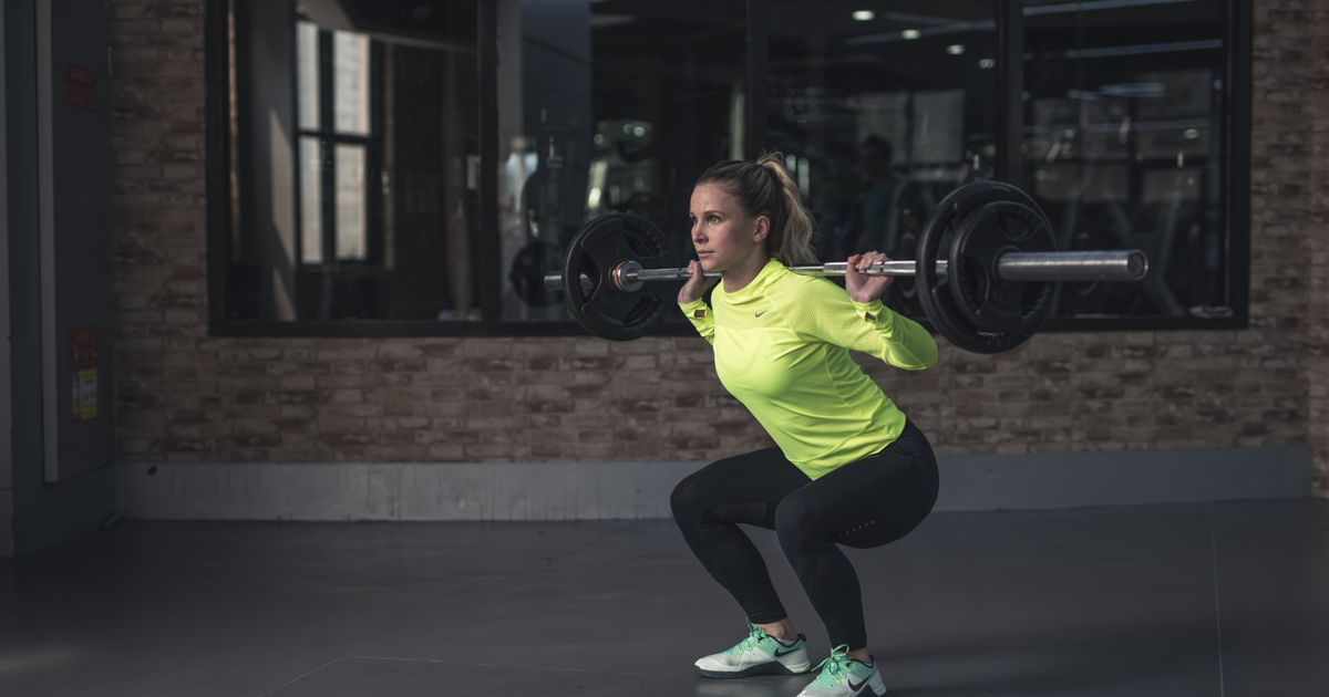 Woman performing a weighted barbell squat in a gym, the lift with the largest average strength gains in our log data