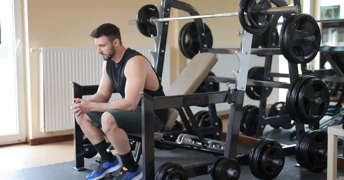 Tired lifter resting during a deload week in the gym