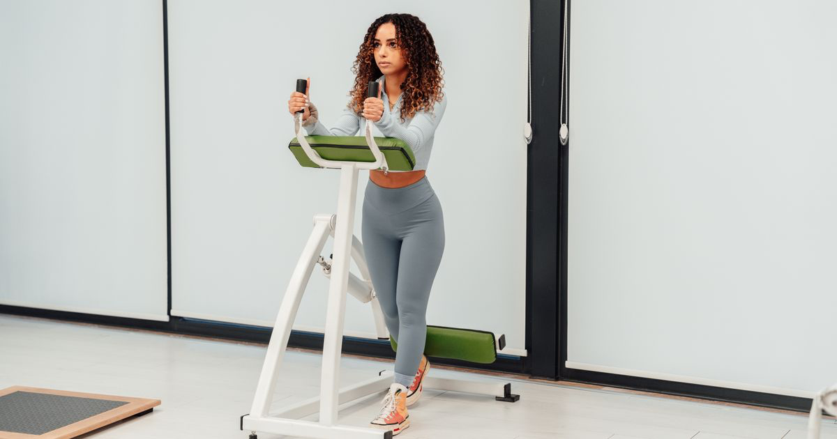 Woman training on a resistance machine in a gym, the kind of lifting compared against blood flow restriction training in the study