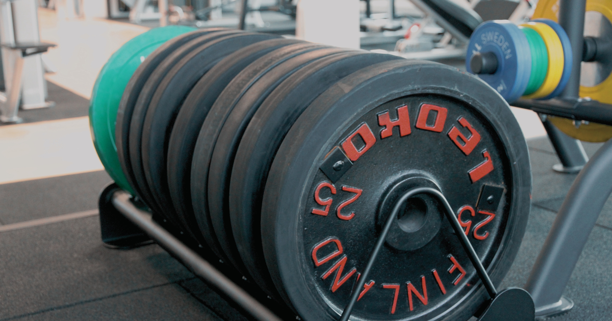 Gym weight plates on a rack, used to calculate an estimated 1RM without maxing out