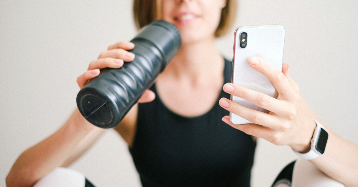 Lifter comparing Fitbod vs Hevy workout tracking apps on a phone at the gym