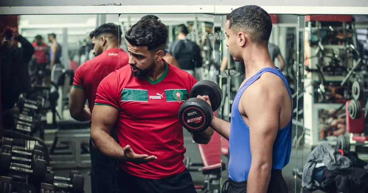 Training partner standing by during a dumbbell curl, the kind of set where forced reps are easy to assist