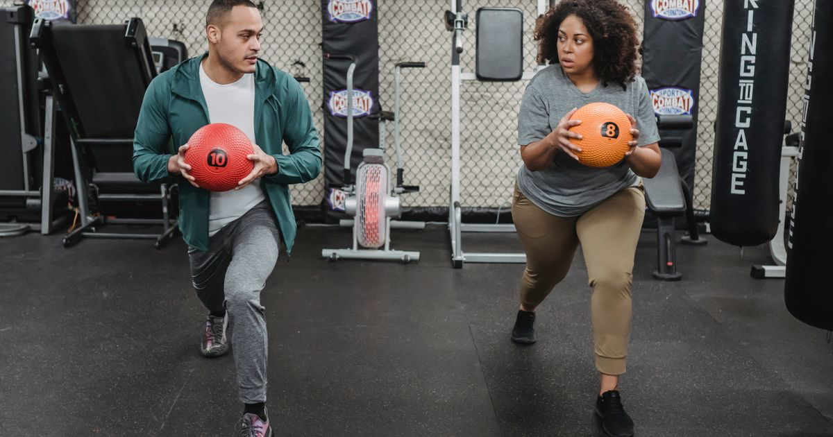 Two athletes doing lunges in a gym demonstrating how to do lunges with good form