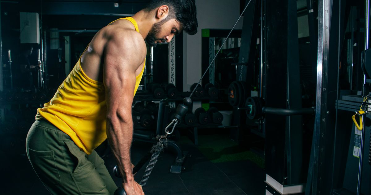 Man training at a gym cable machine, illustrating how to do a tricep pushdown