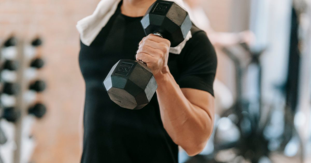 Lifter performing a heavy dumbbell set in a gym, the activation set that starts a myo-reps cluster