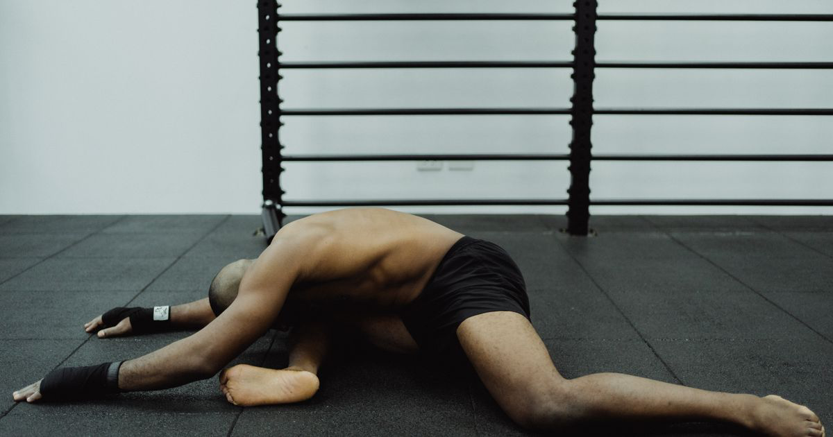 Man stretching in a wide straddle position on a gym floor