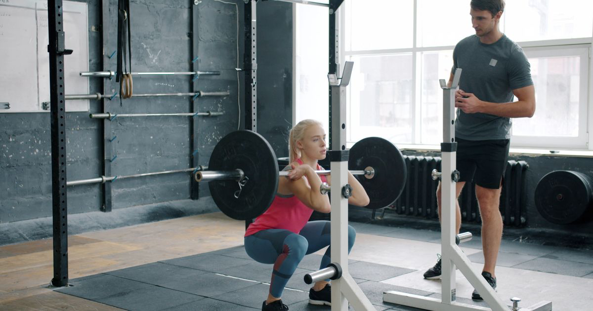 A lifter performing a barbell front squat in a gym, the core lift in the StrongLifts 5x5 program