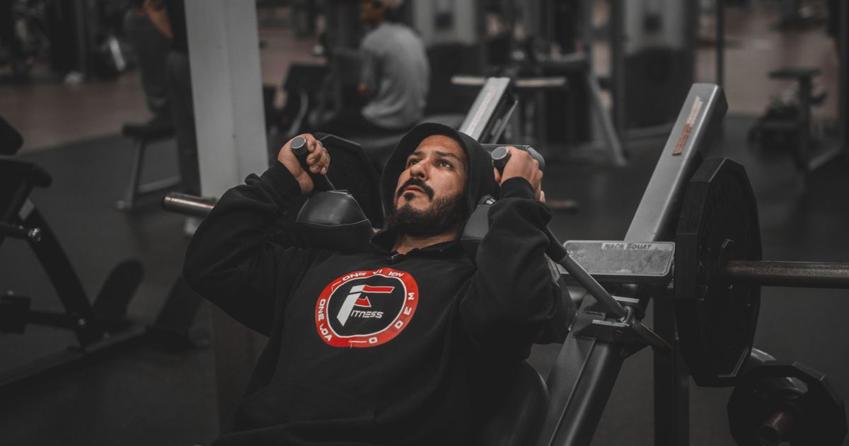 Lifter pressing a barbell on a bench in a gym, the kind of session a workout template saves you retyping
